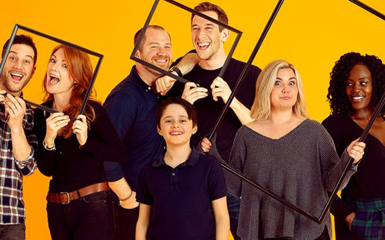 Cast of "Falsettos" posing with picture frames against a yellow background.
