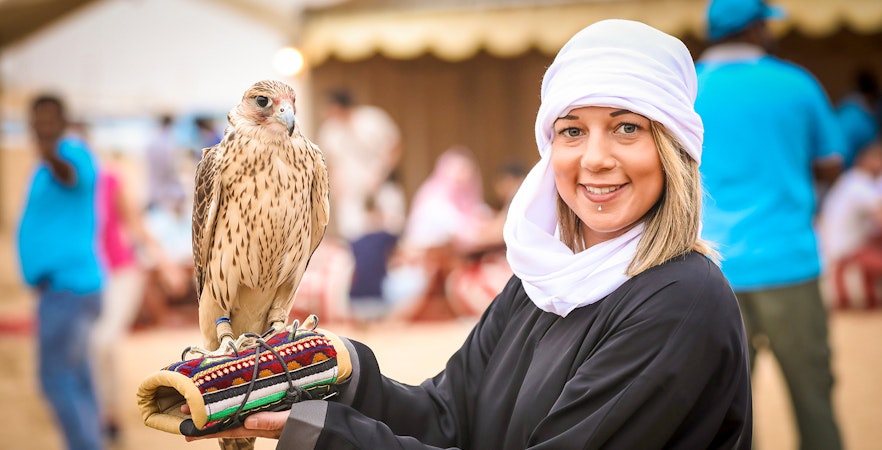 Person holding a falcon at desert Safari.