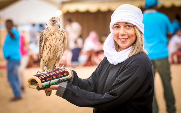 Person holding a falcon at Al Marmoon Oasis Bedouin Camp Heritage Safari.