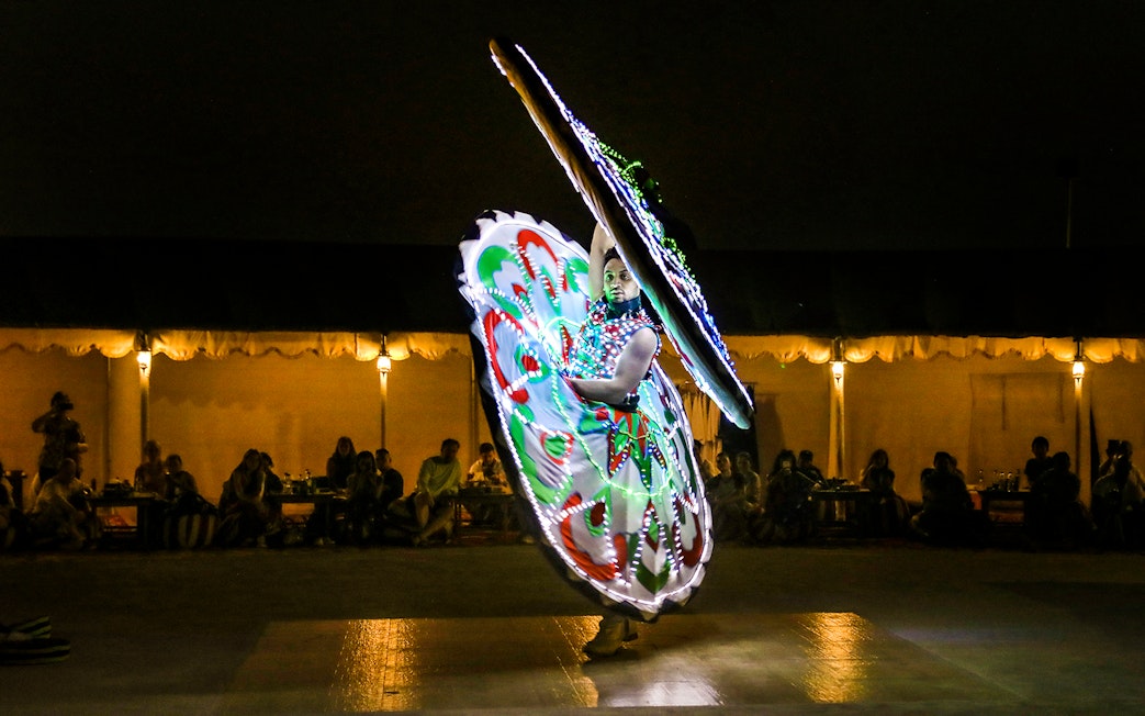 Desert safari performer in colorful illuminated costume during evening show.