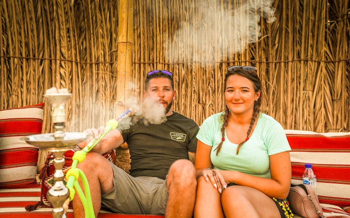 Couple enjoying shisha in a Bedouin tent during an overnight desert safari.