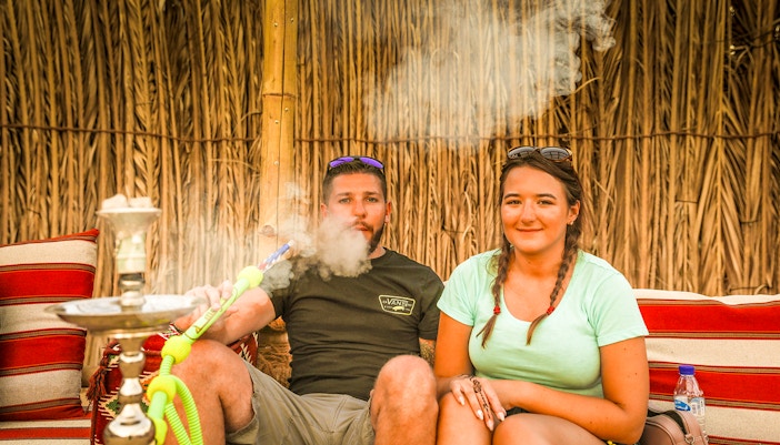 Couple enjoying shisha in a Bedouin tent during an overnight desert safari.
