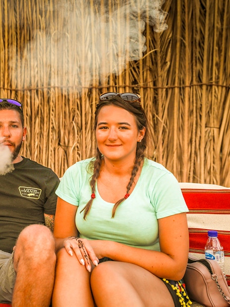 Couple enjoying shisha in a Bedouin tent during an overnight desert safari.