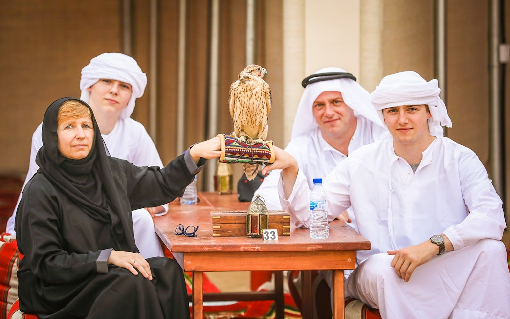 Group enjoying Bedouin desert safari with falconry experience in traditional attire.
