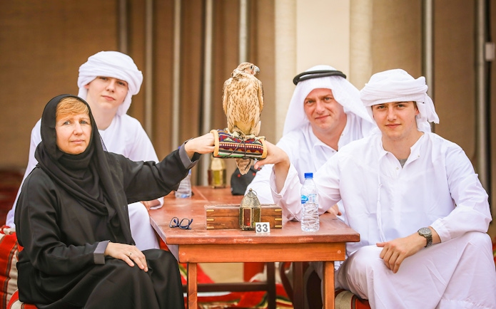 Group enjoying Bedouin desert safari with falconry experience in traditional attire.