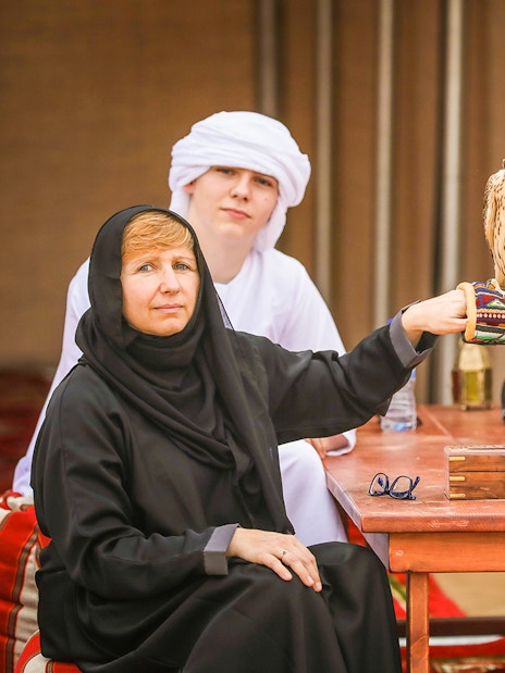 Group enjoying Bedouin desert safari with falconry experience in traditional attire.