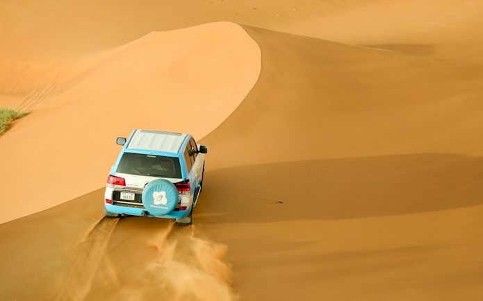 SUV driving over sand dunes during Bedouin desert safari.