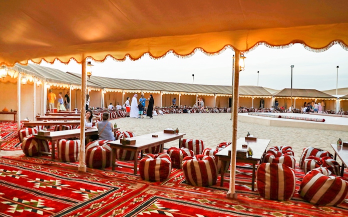 Desert camp setup with traditional seating for Bedouin safari experience.