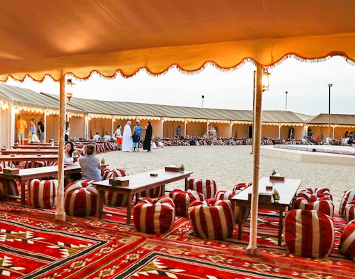 Desert camp setup with traditional seating for Bedouin safari experience.