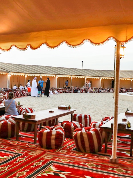 Desert camp setup with traditional seating for Bedouin safari experience.
