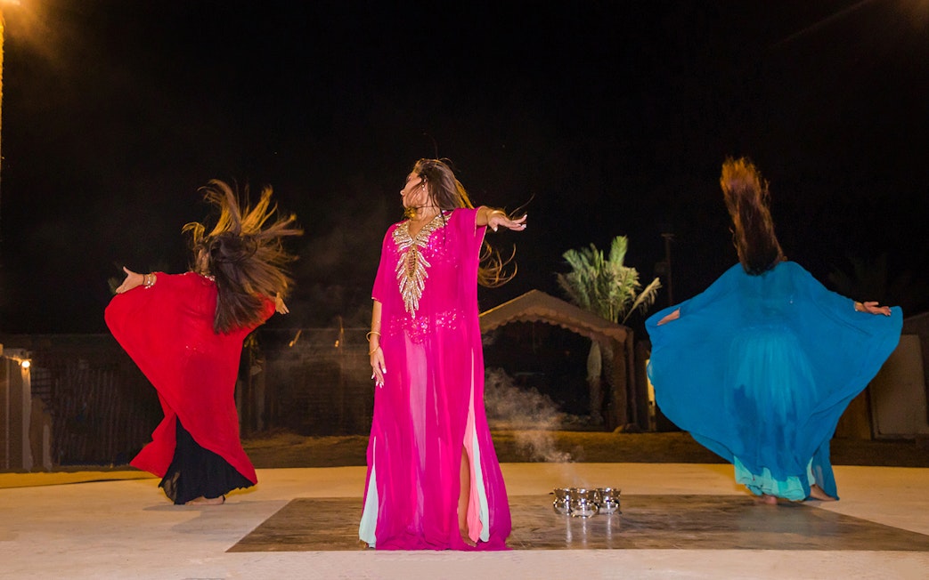 Dancers performing traditional Bedouin dance during desert safari night experience.