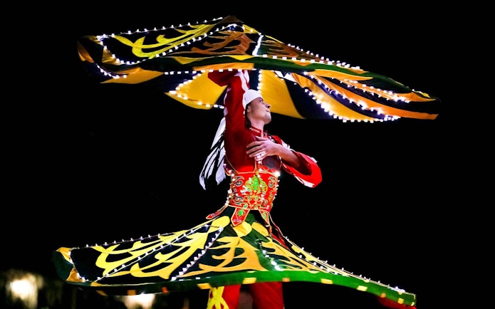 Bedouin dancer performing traditional Tanoura dance during desert safari.