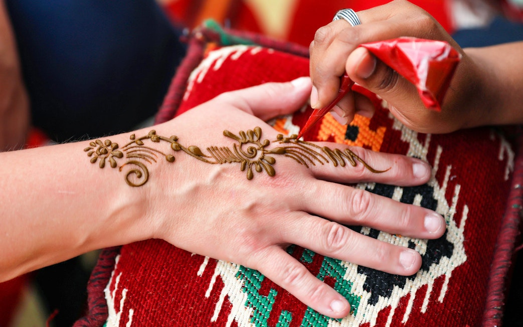 Henna design being applied on a hand during Bedouin desert safari.