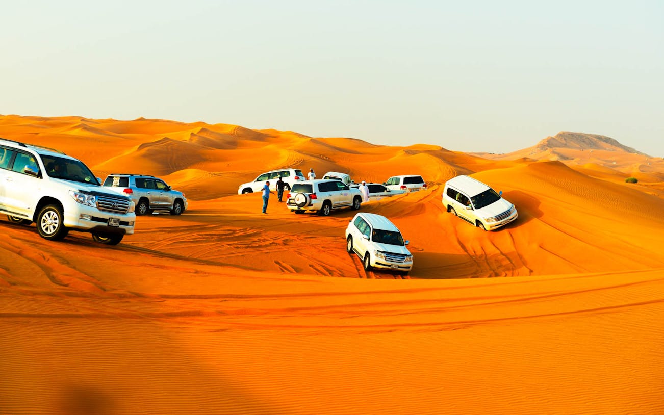 SUVs driving on sand dunes during Arabian Desert Safari.