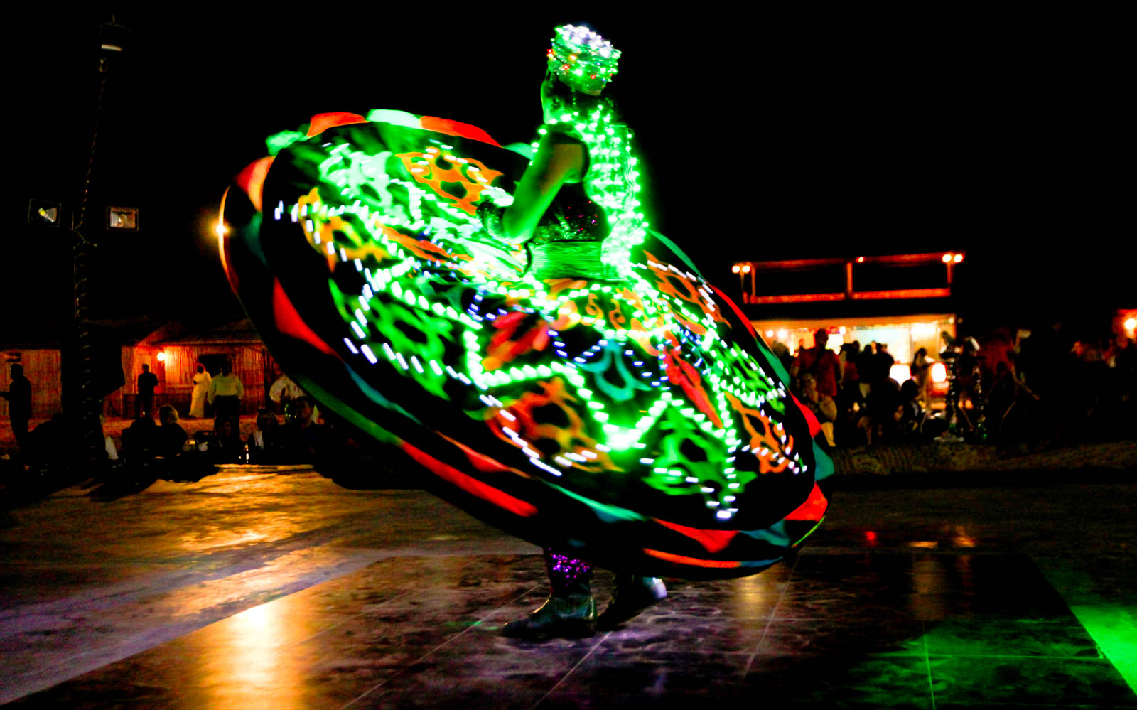 Dancer in illuminated costume performing at Arabian desert safari night show.