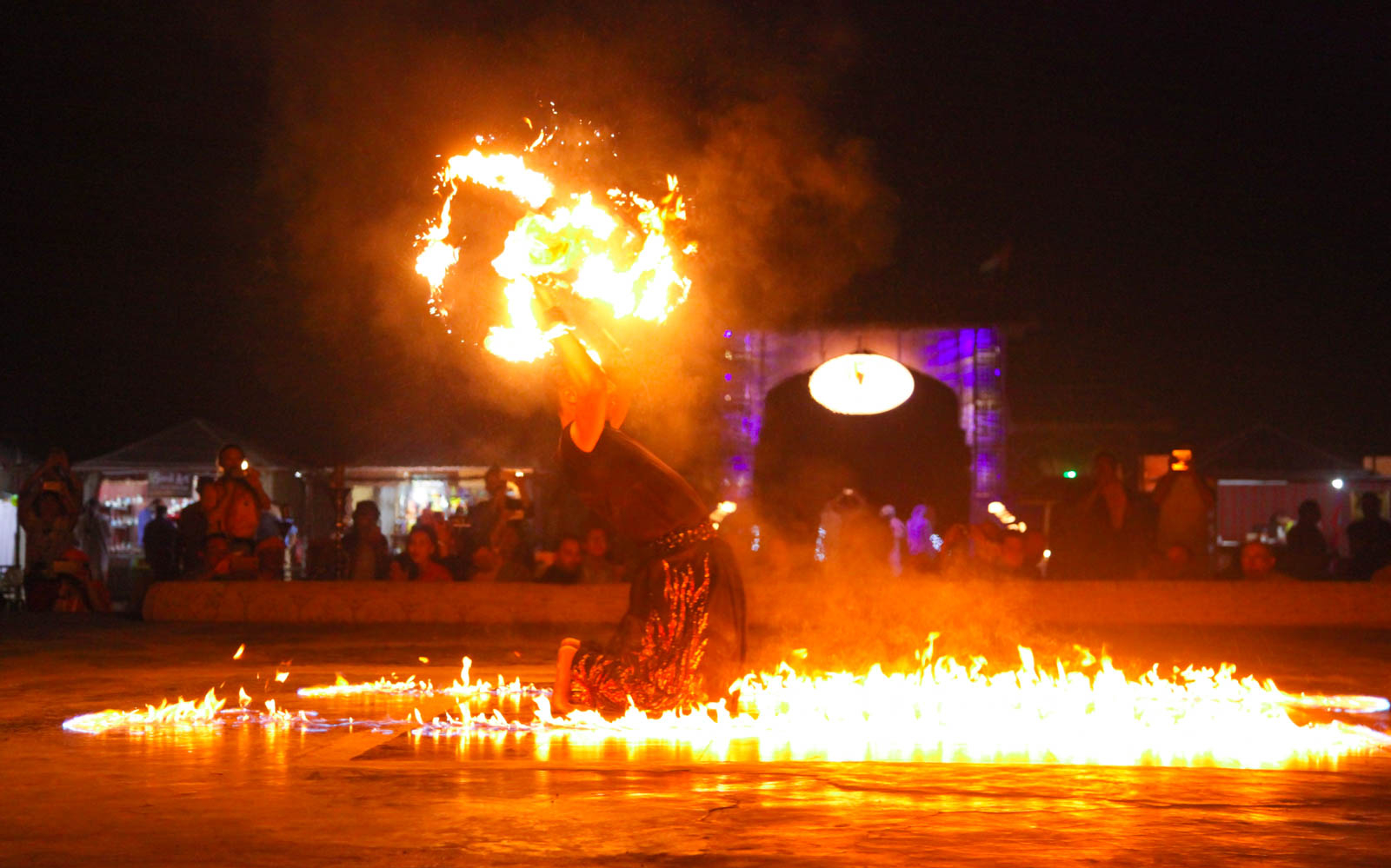 Fire performer at Arabian Dune Desert Safari with audience in background.