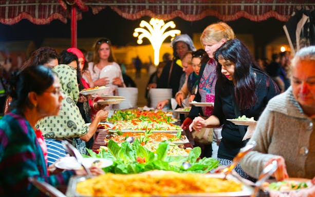 Guests enjoying a buffet dinner during an Arabian Dune Desert Safari experience.
