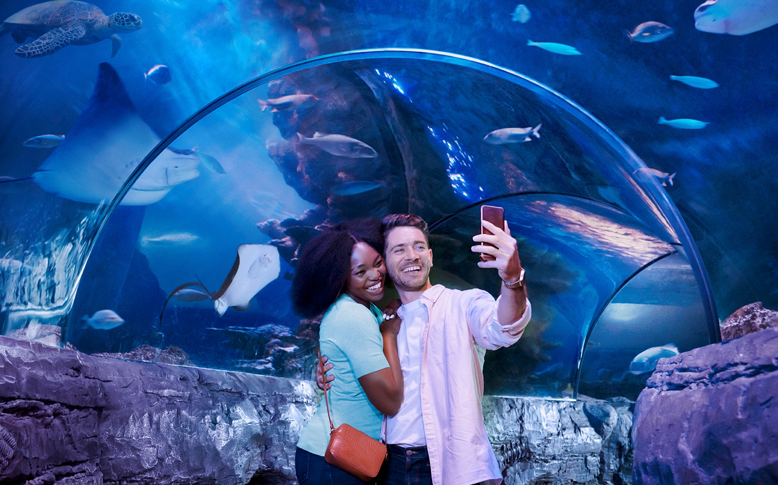 Tourists taking selfie in underwater tunnel at Sealife aquarium.