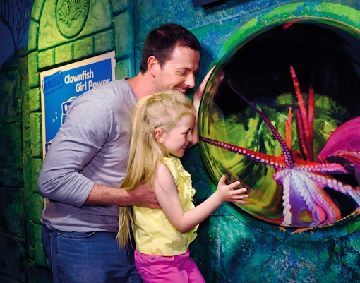 Family observing octopus at Sea Life London Aquarium exhibit.