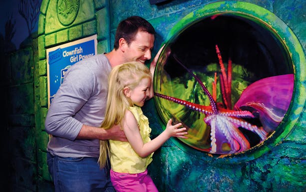 Family observing octopus at Sea Life London Aquarium exhibit.