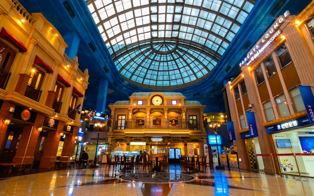 Interior of Kidzania Seoul with a domed glass ceiling and themed storefronts.