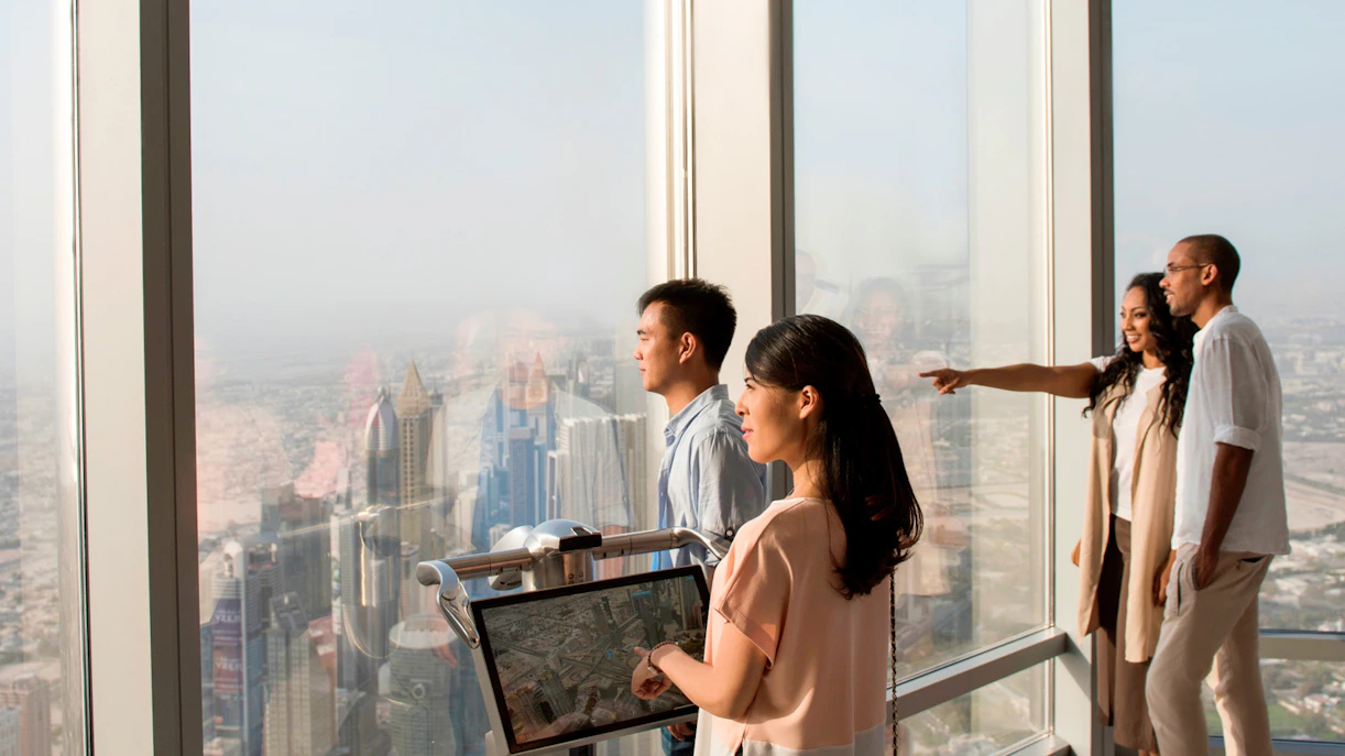 Visitors enjoying the view from Burj Khalifa Level 124, overlooking Dubai skyline.