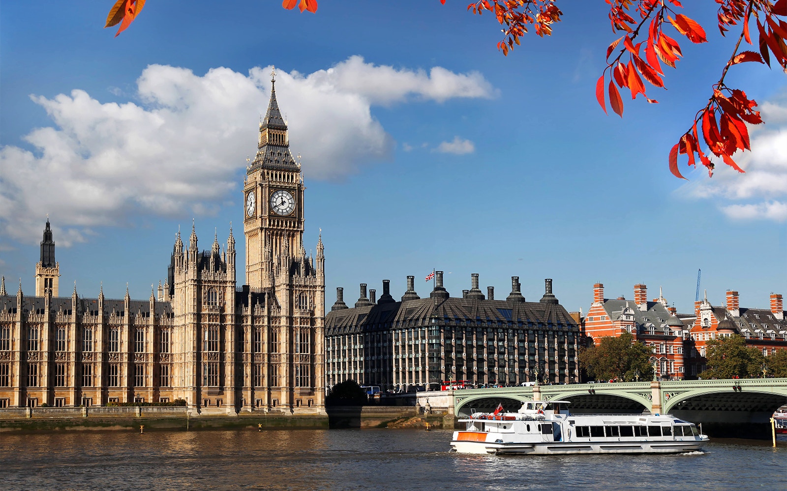 River Thames cruise boat passing under Westminster Bridge with the London Eye in the background.