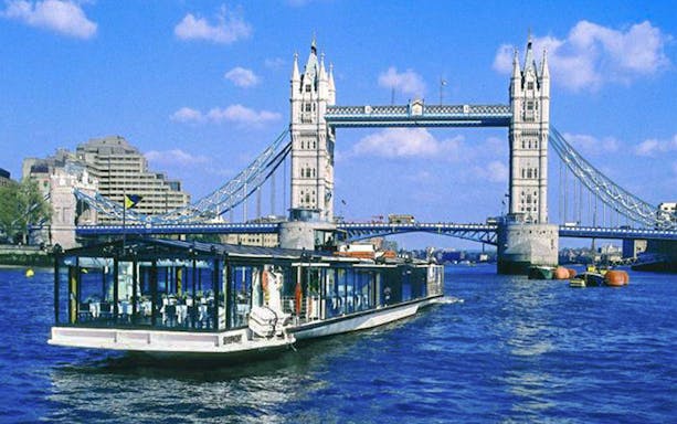 Lunch cruise boat on River Thames with Tower Bridge in London.