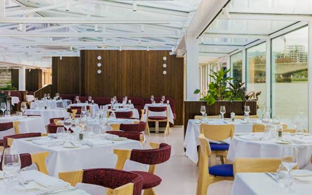 Dining area on Bateaux London lunch cruise with River Thames view.