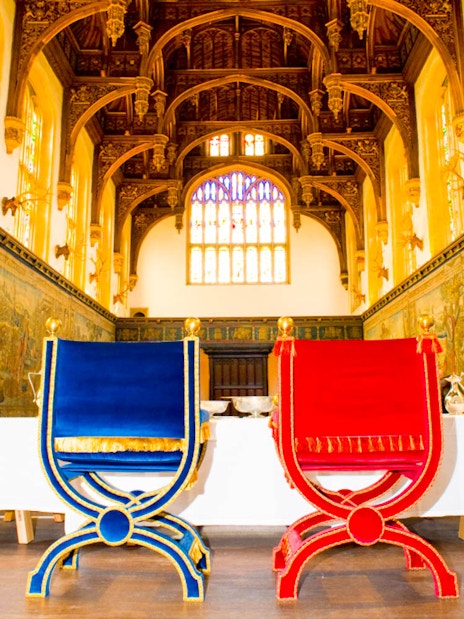 Visitors inside the Great Hall of Hampton Court Palace, London, viewing historic tapestries.