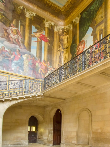 Hampton Court Palace interior with ornate ceiling mural and decorative balcony.