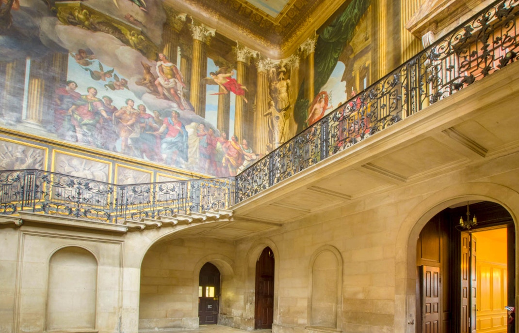 Hampton Court Palace interior with ornate ceiling mural and decorative balcony.