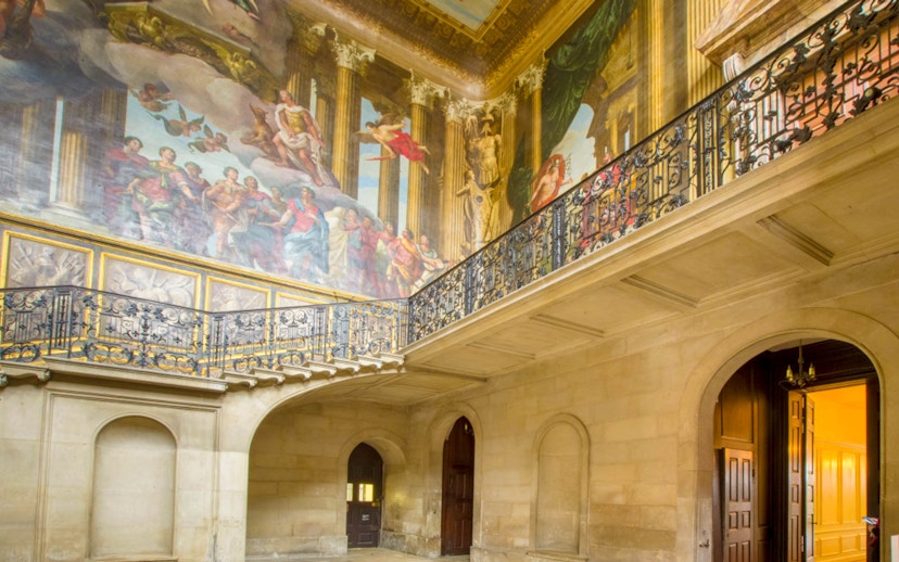 Hampton Court Palace interior with ornate ceiling mural and decorative balcony.