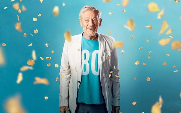 Actor in a white jacket with confetti, promoting "Ian McKellen On Stage" event.