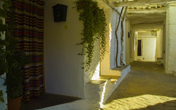 Narrow whitewashed alley in Alpujarras village, Granada day trip.