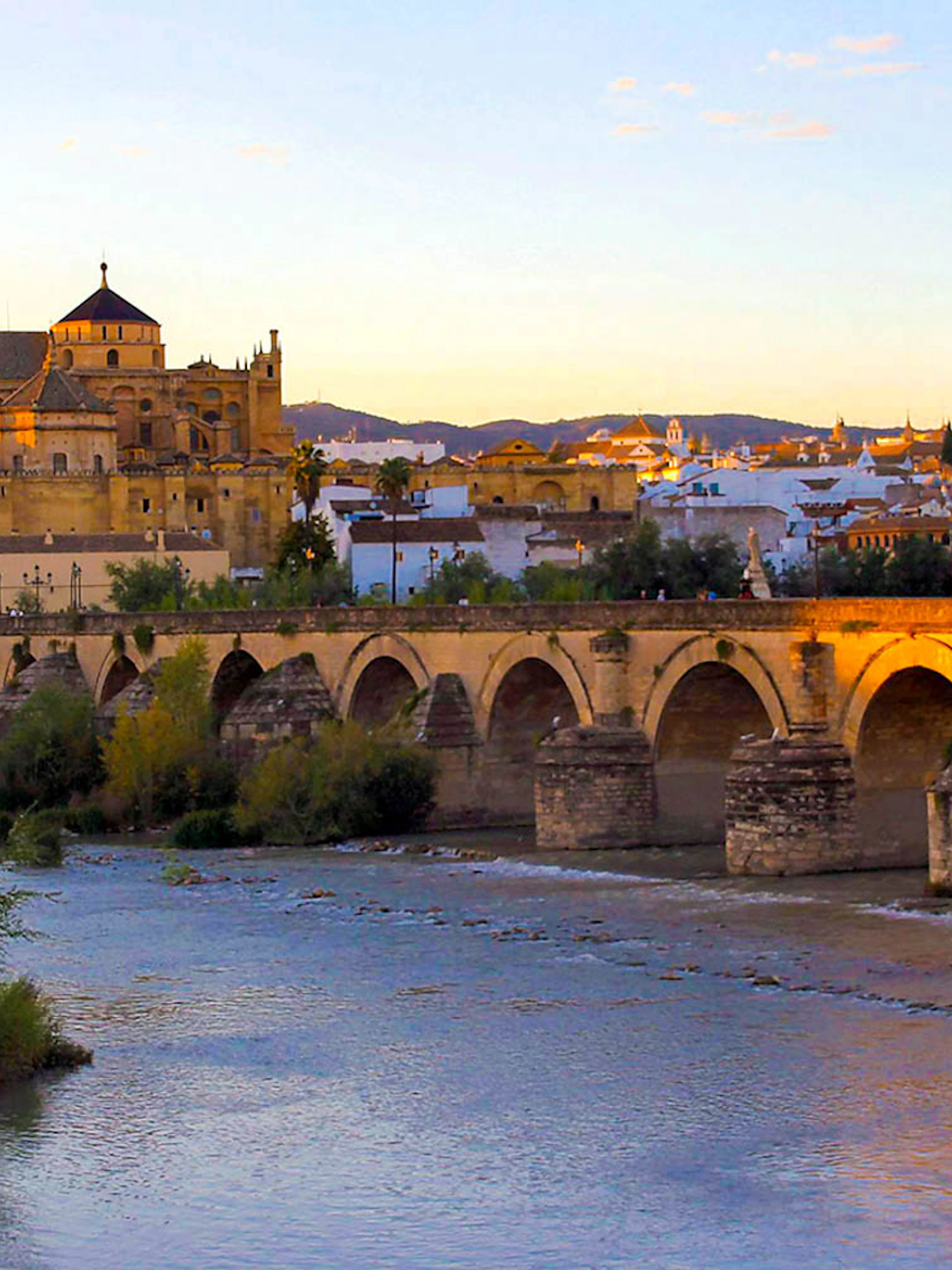 Mosque-Cathedral of Córdoba and Roman Bridge at sunset, view from the Guadalquivir River.