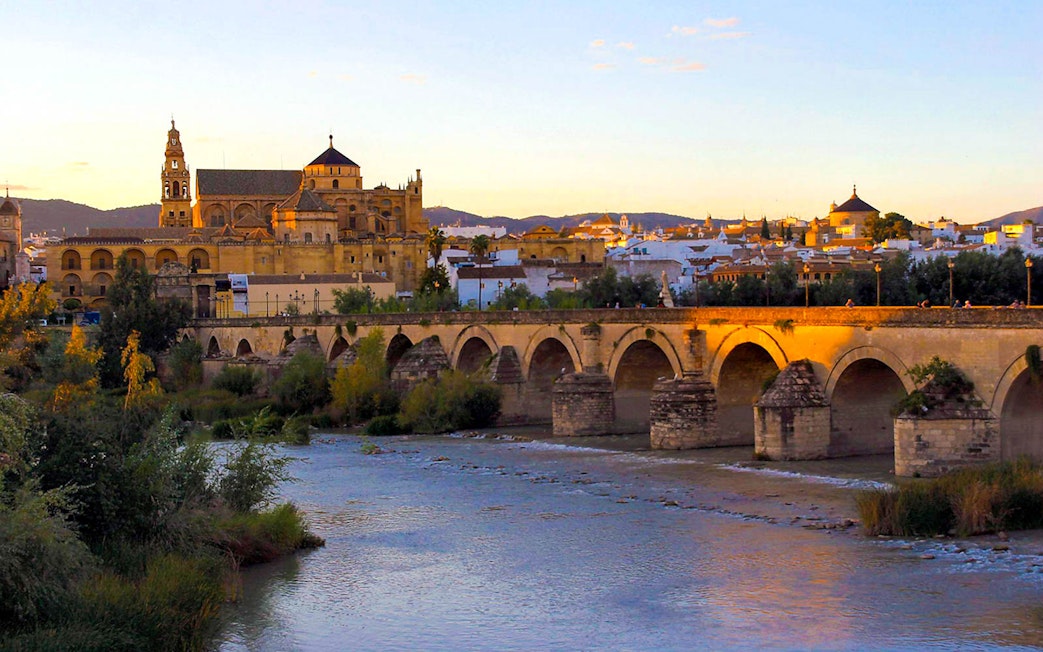 Mosque-Cathedral of Córdoba and Roman Bridge at sunset, view from the Guadalquivir River.