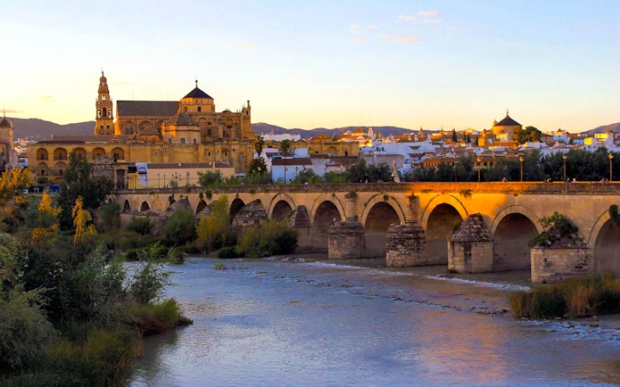 Mosque-Cathedral of Córdoba and Roman Bridge at sunset, view from the Guadalquivir River.