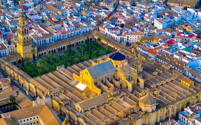 Aerial view of the Mosque-Cathedral of Córdoba, Spain, surrounded by city buildings.