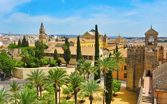 Cordoba Mosque-Cathedral and Alcázar with palm trees and historic architecture.