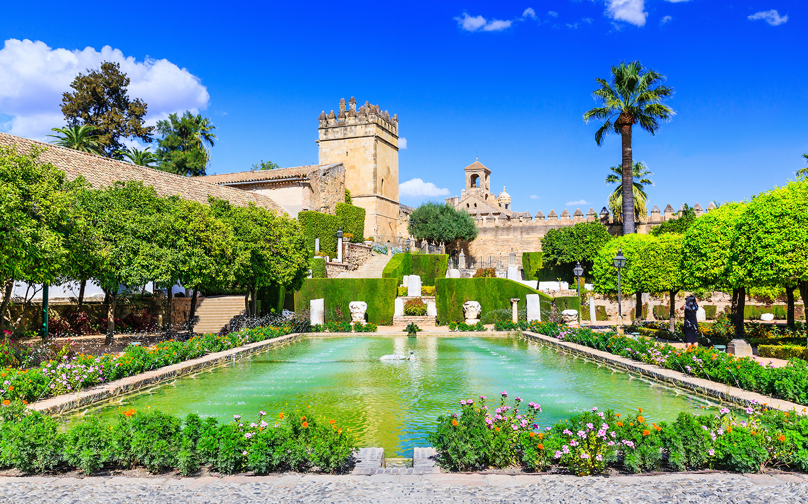 Alcázar gardens with fountain and historic walls in Cordoba, Spain.