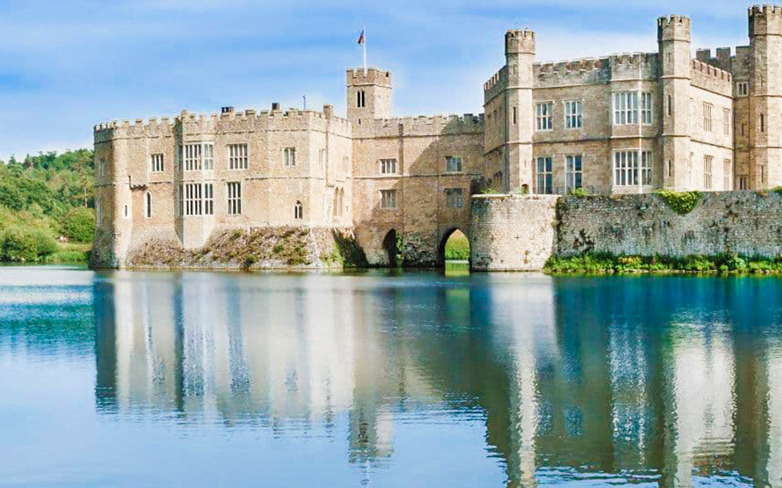 Leeds Castle reflected in a serene lake, part of the Leeds Castle, Canterbury Cathedral & White Cliffs of Dover Tour.