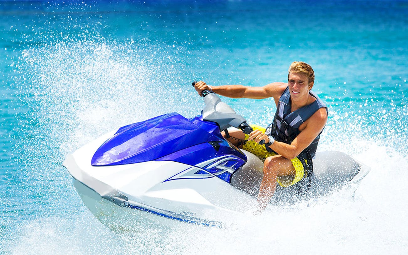 Person riding a premium jet ski on clear blue water.