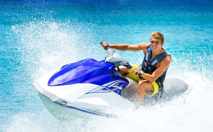 Person riding a premium jet ski on clear blue water.