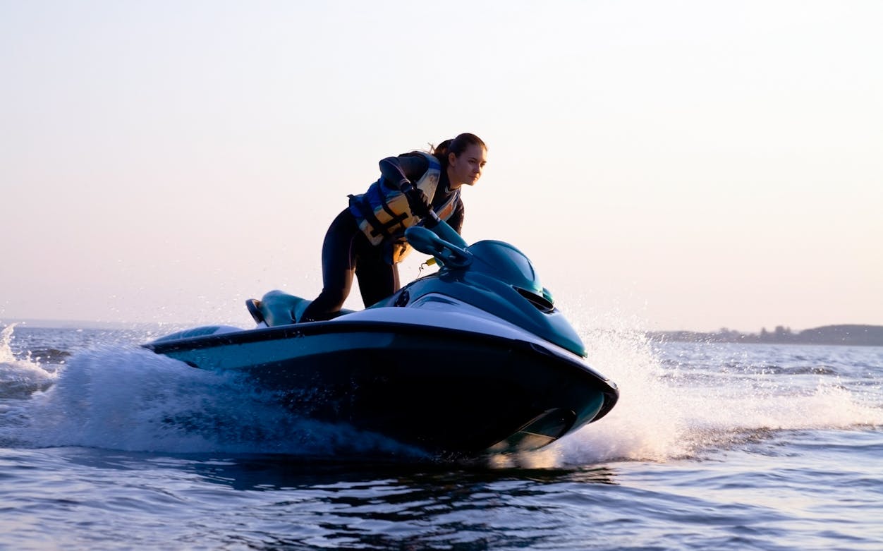Person riding a premium jet ski on open water at sunset.