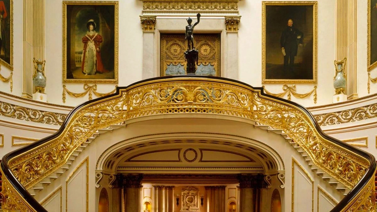 Buckingham Palace State Rooms with ornate staircase and historical portraits.