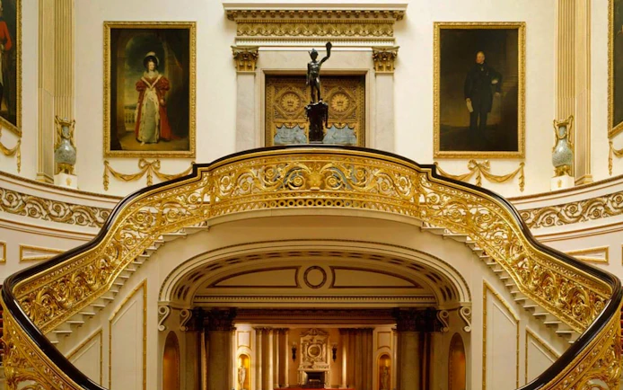 Buckingham Palace State Rooms with ornate staircase and historical portraits.