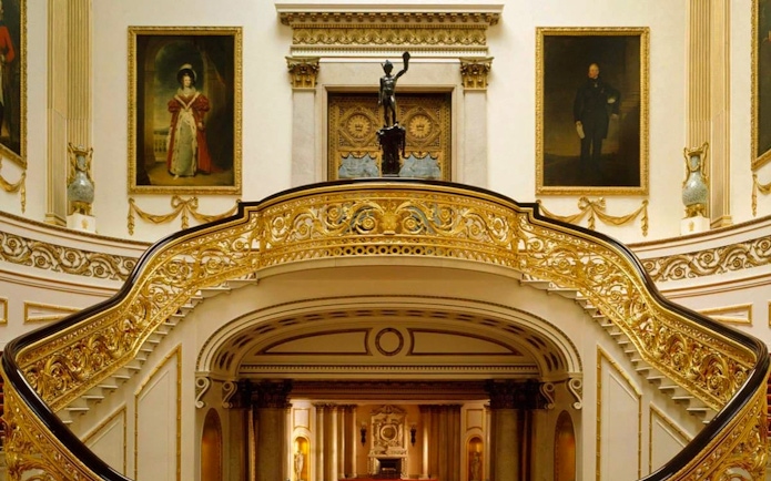 Buckingham Palace State Rooms with ornate staircase and historical portraits.