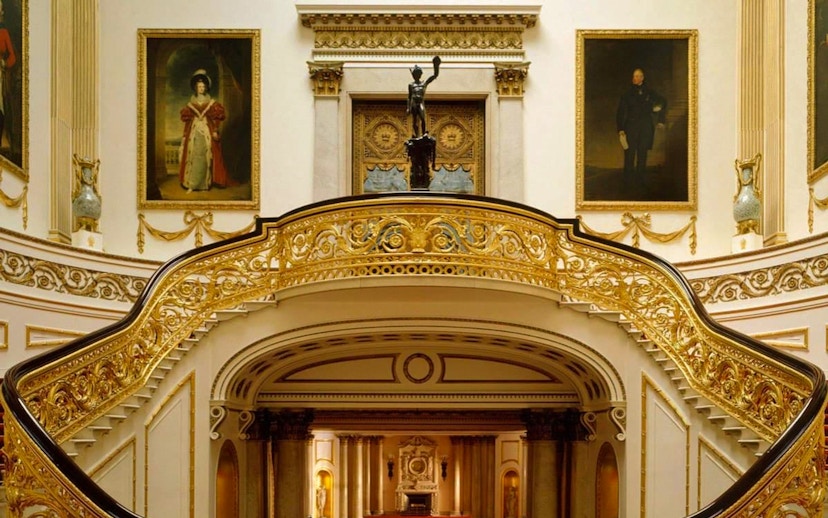 Buckingham Palace State Rooms with ornate staircase and historical portraits.