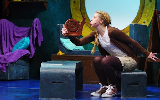 Performer interacting with a snail prop during "The Snail and the Whale" stage show.